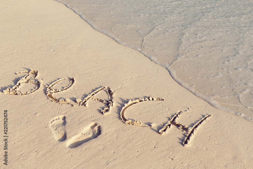 Fototapeta premium Handwritting inscription word BEACH on sand
