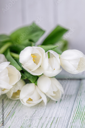 Beautiful white tulips on a light wooden background. Free space