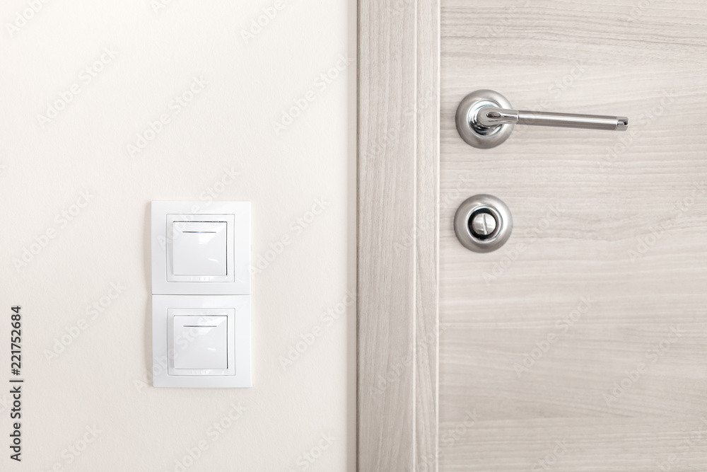 Door handle and white lighting switches on wall Door handle and white lighting switches on wall