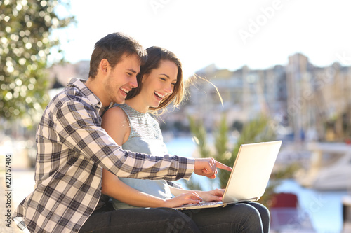 Happy couple uses a laptop on vacation