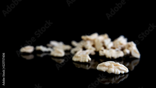 Fresh peeled walnuts scattered on black background with shadows, fresh kernel, healthy food