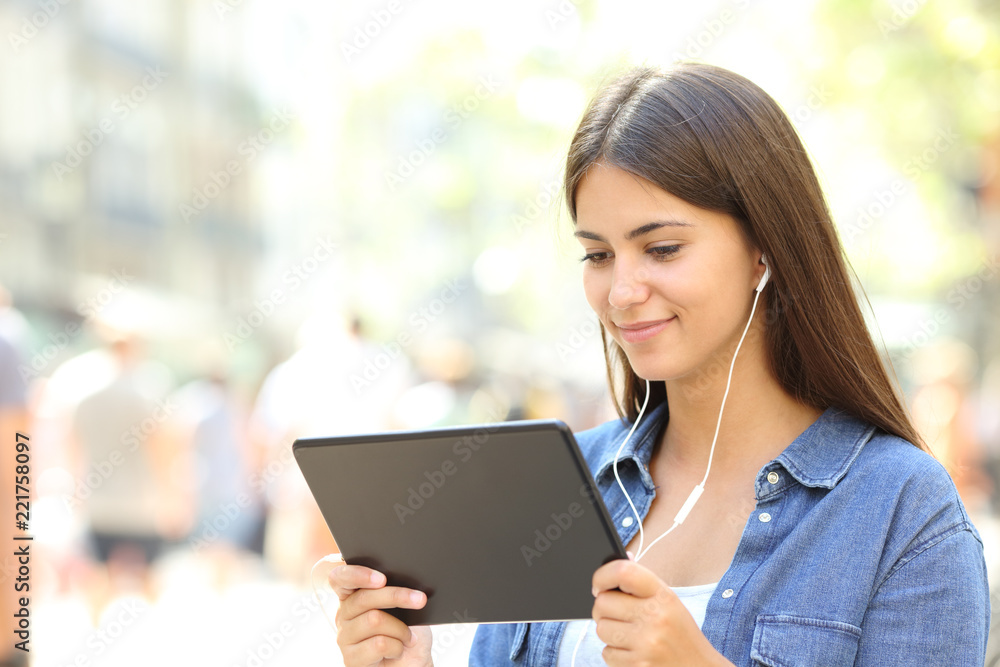 Girl is watching videos in a tablet in the street