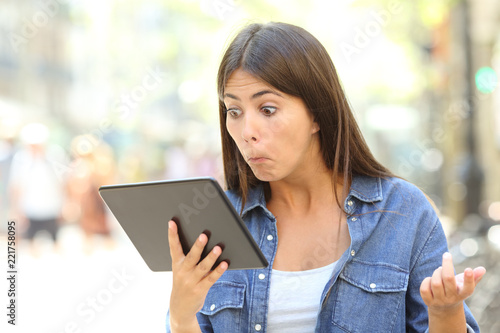 Confused girl with a tablet outdoors