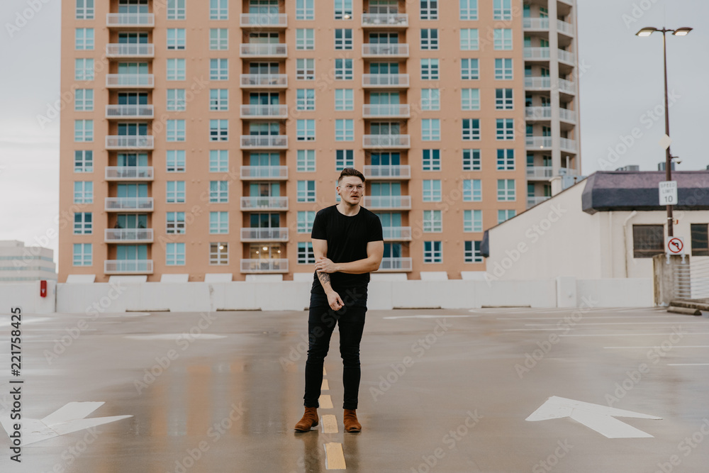 Young Trendy Male Fashion Model in Denim Jacket on Top of a Downtown Parking Garage Young Trendy Male Fashion Model in Denim Jacket on Top of a Downtown Parking Garage