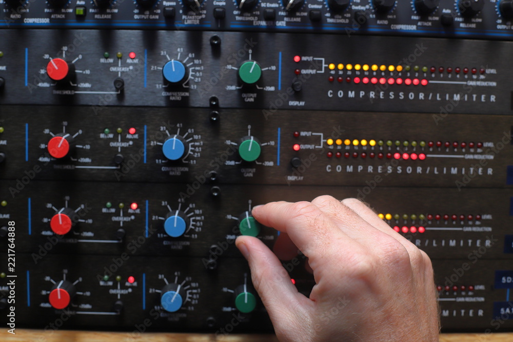 Hands adjusting knobs on sound compressors used for music production and broadcast audio Hands adjusting knobs on sound compressors used for music production and broadcast audio