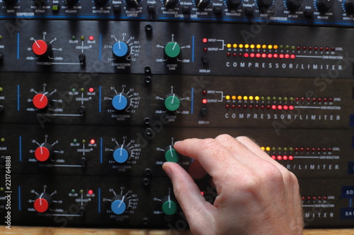 Hands adjusting knobs on sound compressors used for music production and broadcast audio photo