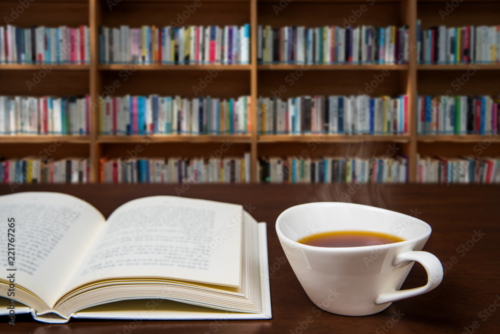 a book open on the desk with a cup of coffee. a book open on the desk with a cup of coffee.