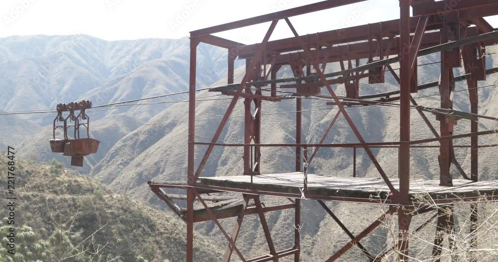 Old Cable Car Chilecito-La Mejicana mine. Detail of hanging wagons from cable and platform of third station. Mountains and vegetation at background. Camera moves sideways. National Heritage