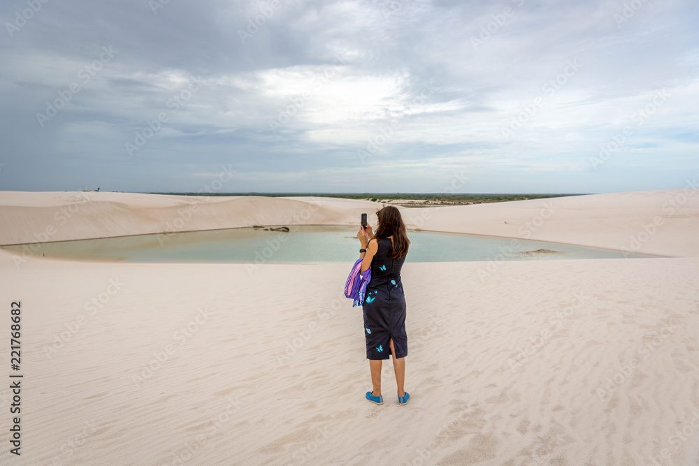 Young woman snapping a cellphone video at a cloudy day in the lencois maranhenses national park in Brazil Young woman snapping a cellphone video at a cloudy day in the lencois maranhenses national park in Brazil
