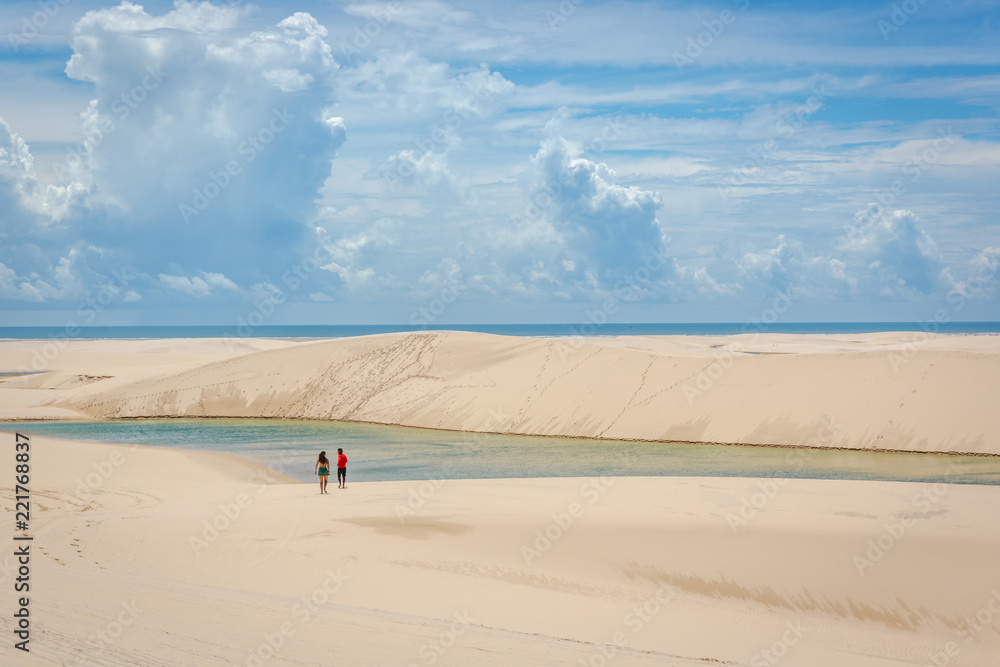 Young couple heading to a natural swimming pool through the sandy dunes in Brazil Young couple heading to a natural swimming pool through the sandy dunes in Brazil