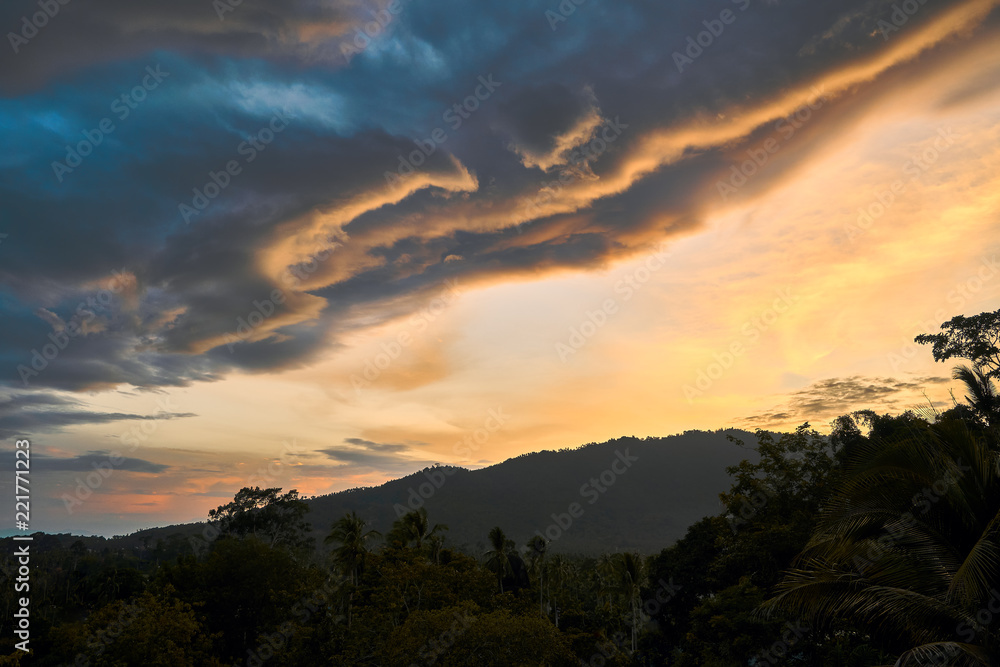 Fototapeta premium Dramatic clouds against the backdrop of mountains at sunset on a tropical island. 4k time lapse
