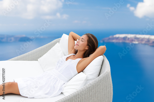 Luxury home lifestyle woman relaxing on comfortable outdoor sofa daybed chair sleeping sun tanning breathing fresh air on ocean background. Asian girl in comfort. © Maridav