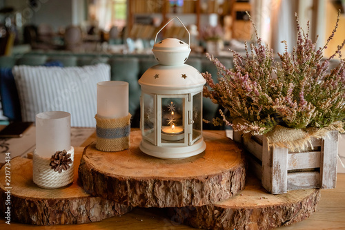 White burning lantern, heather in wooden box on a wooden table decorated in autumnal style, pine cornes, walnuts and candles in rustic style, the concept of autumn. Wedding decor
