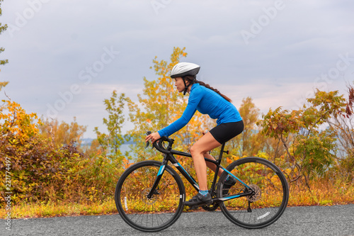 Fototapeta Naklejka Na Ścianę i Meble -  Biking road bike girl in autumn. Active sport fitness exercise in fall season.