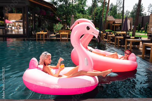 Perfect vacation. Joyful pleasant woman drinking a tasty cocktail while relaxing in the air flamingo © zinkevych