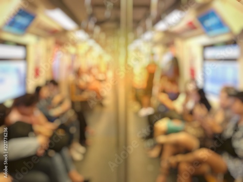 Blurred image of city people lifestyle background, inside the train. passenger sitting in underground waiting to go at work. Busy moment of persons in cab. Transport concept and technology addicted.