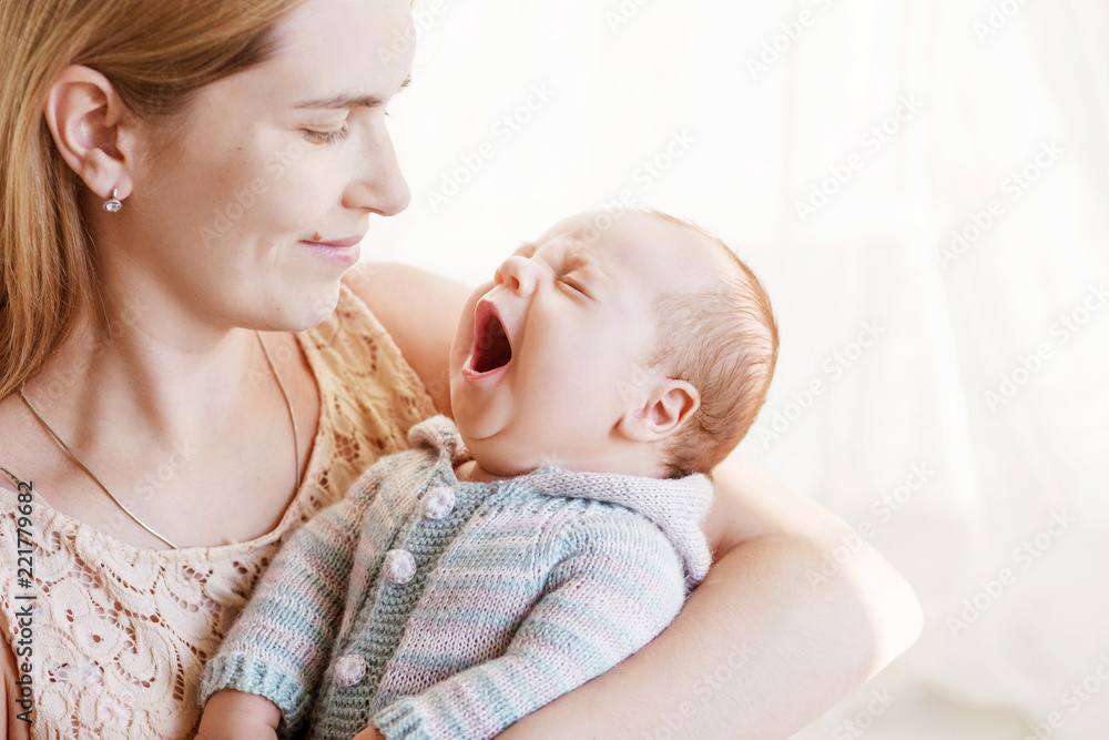 Pretty woman holding yawning newborn baby in her arms. Close up image. Motherhood concept. Happy family concept Pretty woman holding yawning newborn baby in her arms. Close up image. Motherhood concept. Happy family concept