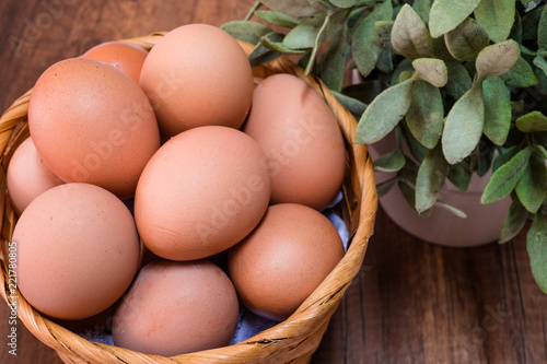 Fresh chicken eggs in basket on wooden table with space for text