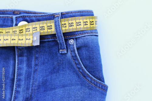 Jeans and measuring subject for weight loss on blue background