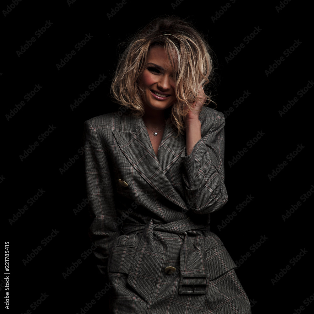 laughing blonde woman wearing grey plaid suit fixes her hair laughing blonde woman wearing grey plaid suit fixes her hair