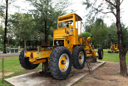 Road grader parking..Discharge old construction machine with six rubber wheels parking in public park for children playground..