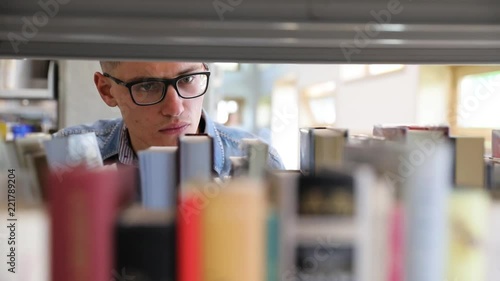 Man Looking For Book On Bookshelves At Library At College