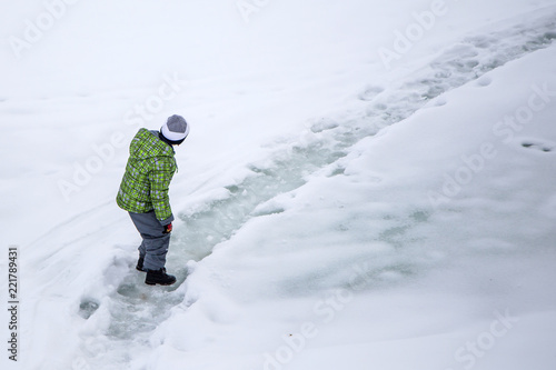 the boy is walking on a slippery icy path