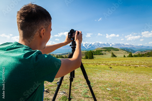 Travel  hiking man shoooting  mountain landscape. Tourist professional photographer on  vacation shooting,   camera on tripod. photo