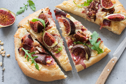 Flatbread with figs, ham, cheese and arugula. Gourmet pizza with prosciutto. Closeup view