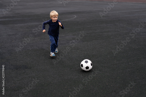 Fototapeta Naklejka Na Ścianę i Meble -  active lifestyle in a modern city - little boy playing with a soccer ball at the stadium