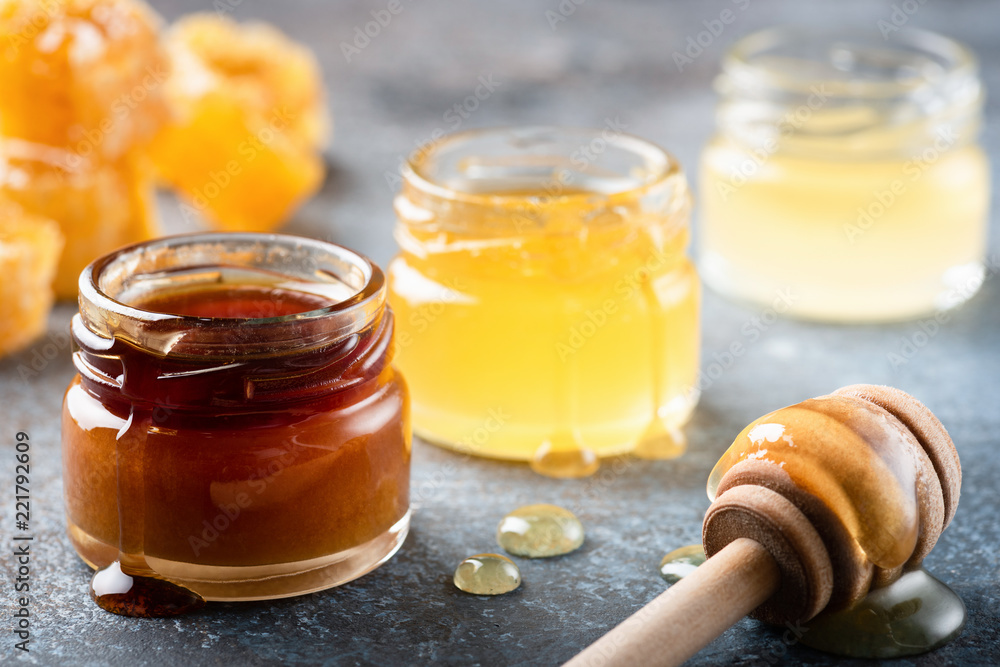 Honey in jar with wooden honey dipper, liquid honey. Closeup view Honey in jar with wooden honey dipper, liquid honey. Closeup view