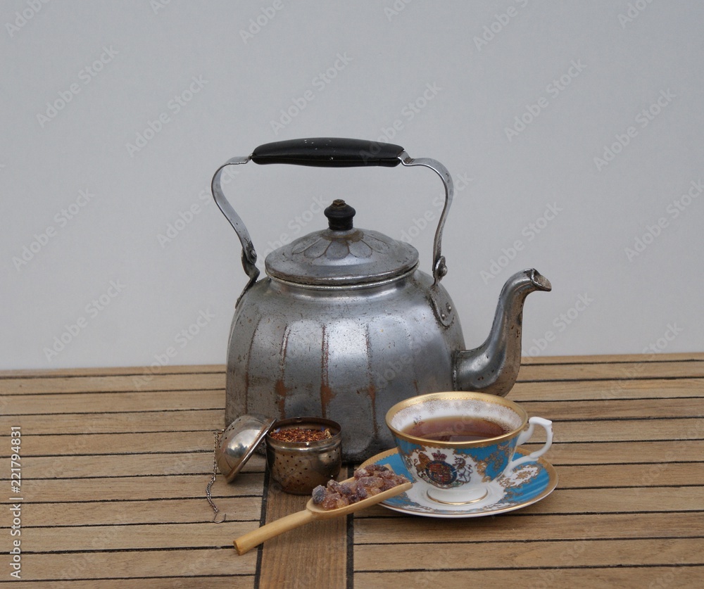 Tee zubereitet in einem alten Wasserkessel mit Holzgriff, Teetasse, Teeei und Kandis 