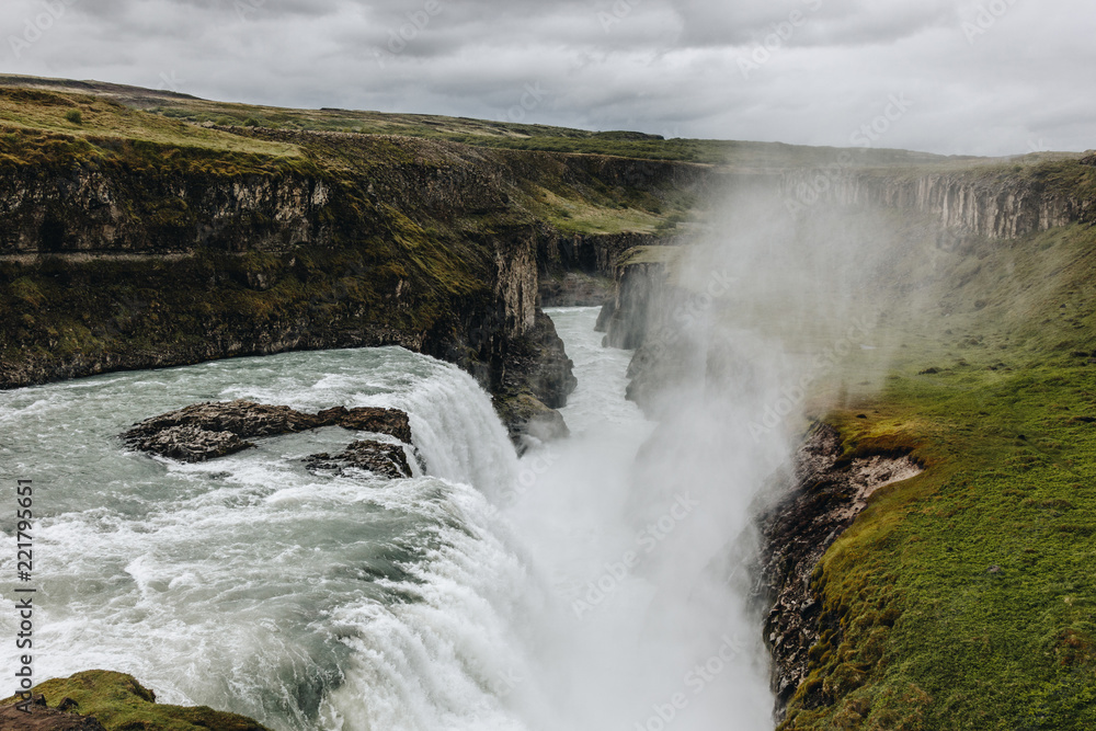 scenic view of steam above beautiful Gullfoss waterfall flowing through highlands in Iceland scenic view of steam above beautiful Gullfoss waterfall flowing through highlands in Iceland