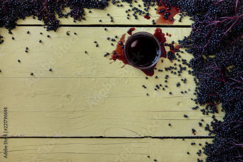 Frische reife violette schwarze Holunderbeeren und Holundersaft auf rustikalem grauem gelbem Tisch hintergrund mit freiem Raum für Ihren Text photo