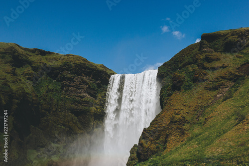 scenic view of waterfall Skogafoss against bright blue sky in Iceland