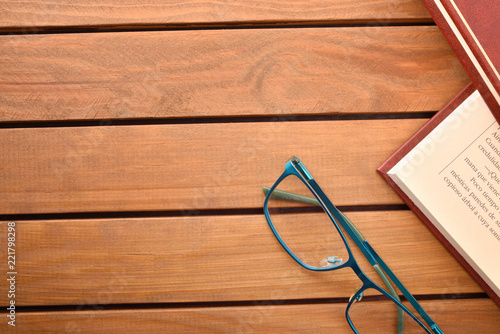 Reading glasses on wood table with books top