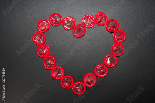 The heart is laid out with red condoms on a black background