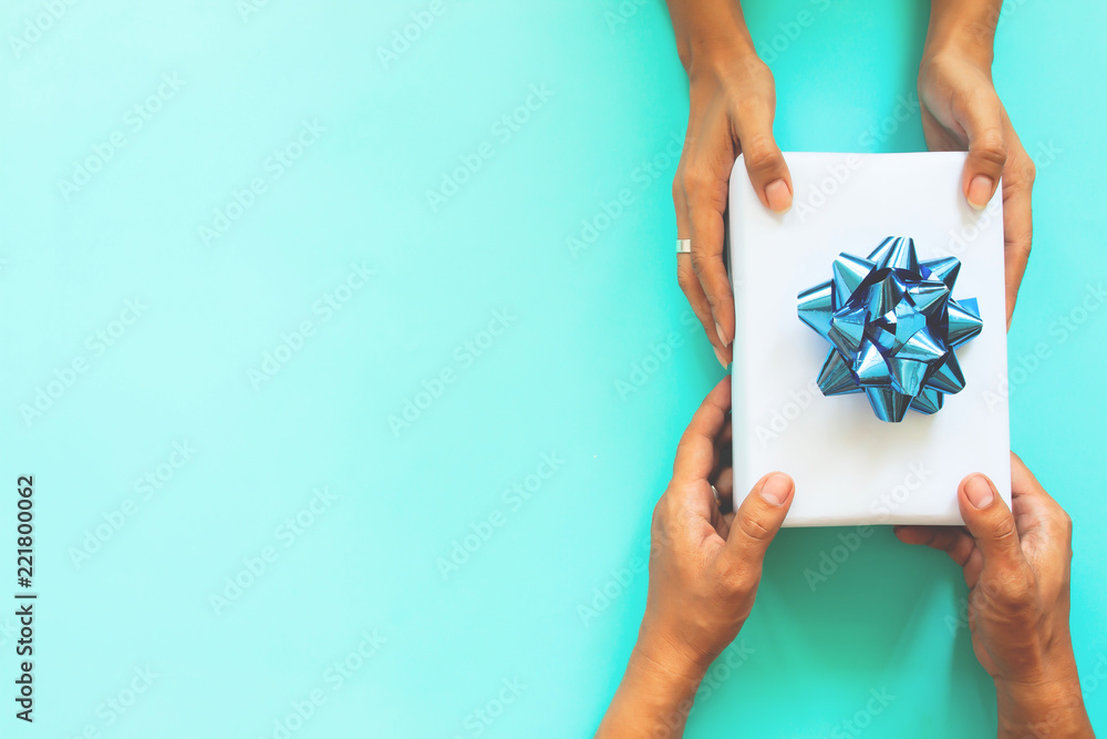 Top view woman and man hands giving gift box on pastel color background Top view woman and man hands giving gift box on pastel color background