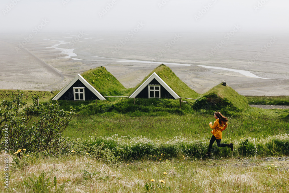 Φωτογραφία distant view of young woman running near Black farmhouses in Skaftafell National