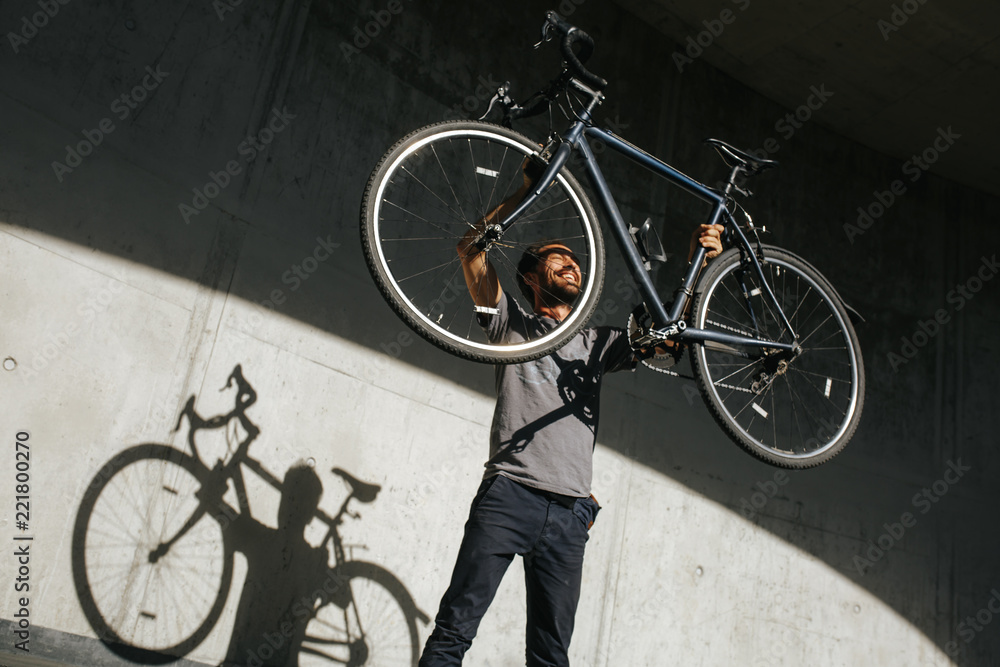 Naklejka premium Mann hebt voller Freude sein Fahrrad in die Luft