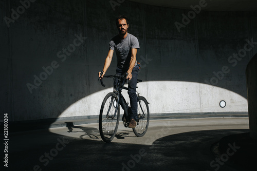 Vorderansicht von männlichem Radfahrer, der in einer urbanen Landschaft auf seinem Fahrrad fährt
