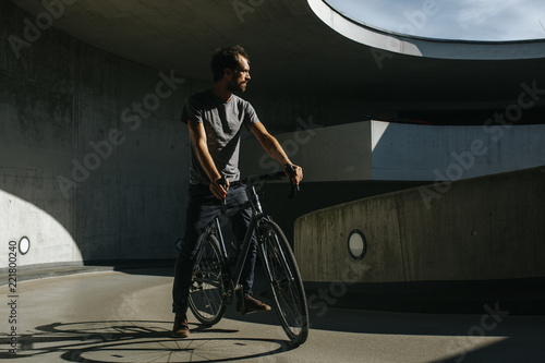 Fototapeta Naklejka Na Ścianę i Meble -  Vorderansicht von männlichem Radfahrer, der in einer urbanen Landschaft auf seinem Fahrrad fährt