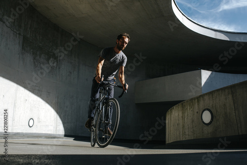 Vorderansicht von männlichem Radfahrer, der in einer urbanen Landschaft auf seinem Fahrrad fährt