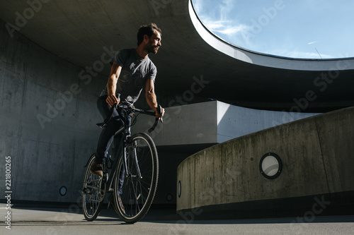Fototapeta Naklejka Na Ścianę i Meble -  Vorderansicht von männlichem Radfahrer, der in einer urbanen Landschaft auf seinem Fahrrad fährt