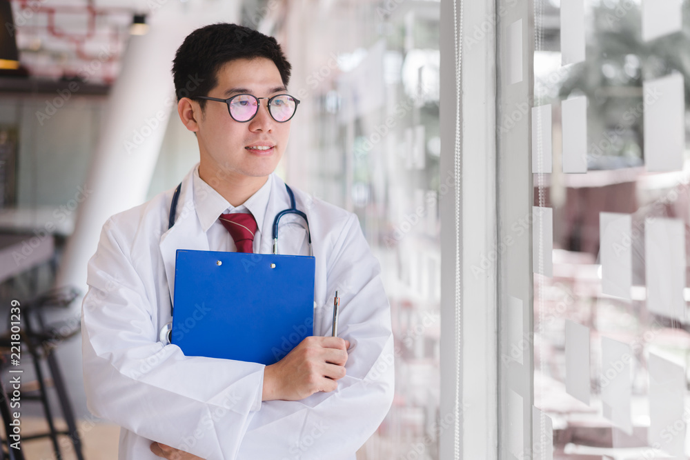 Asian smart doctor standing arms crossed and holding a blue document file. Asian smart doctor standing arms crossed and holding a blue document file.