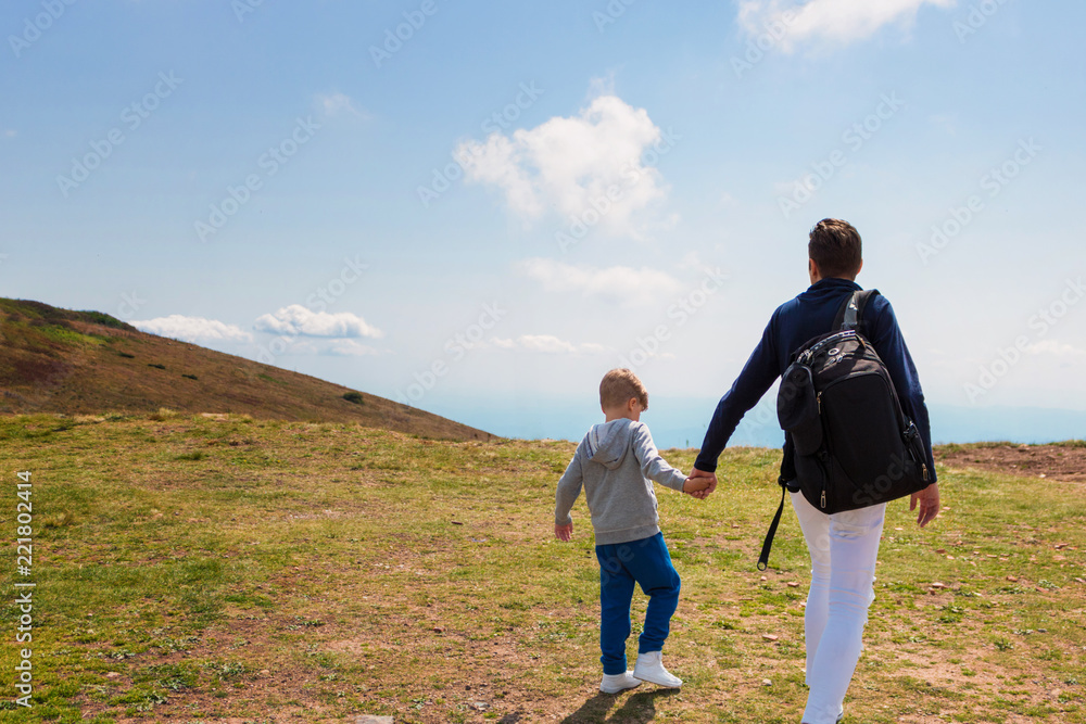 Father and son holding hands and hiking in mountains. Father and son holding hands and hiking in mountains.