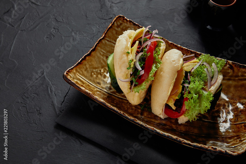 close-up view of delicious braised spicy pork buns with vegetables on plate