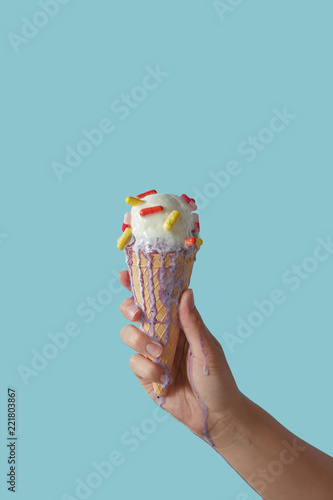 Waffle cone with melting ice cream and pills, holds female hand on blue background with copy space. photo