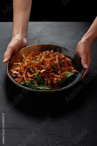 cropped shot of person holding plate with delicious japanese dish with katsuobushi, dried bonito shavings