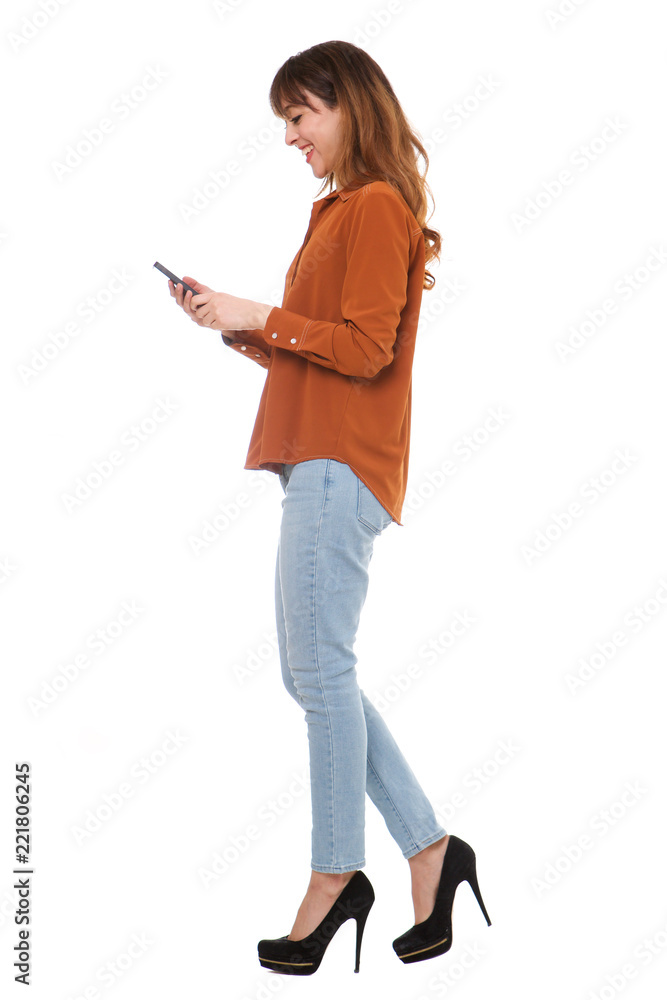 side portrait of young woman walking and looking at cellphone on isolated white background side portrait of young woman walking and looking at cellphone on isolated white background